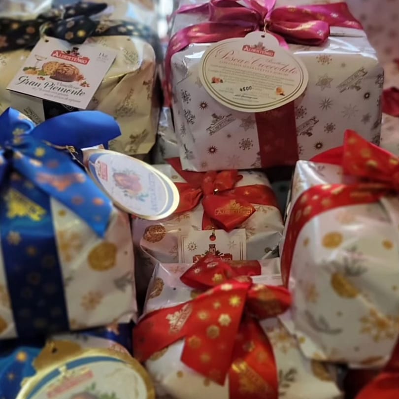 Italian panettone and pandoro cakes from Albertengo, wrapped with festive bows, on display at Tino's Delicatessen.