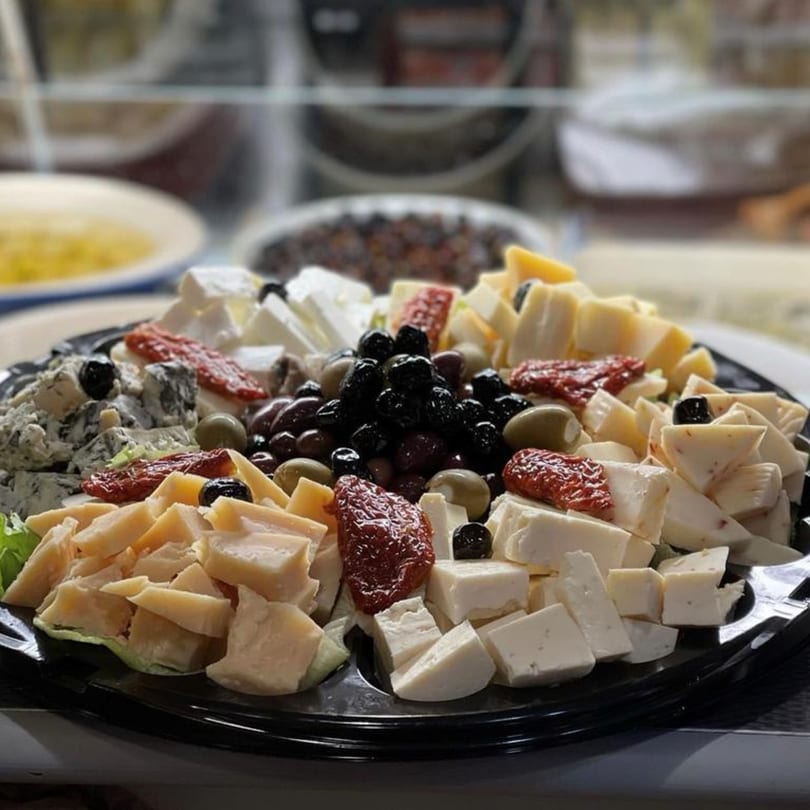 A platter of various Italian cheeses, olives, and sun-dried tomatoes from Tino's Delicatessen.