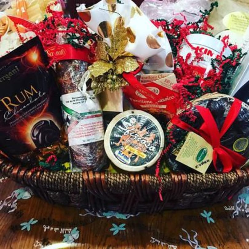A gift basket from Tino's Delicatessen filled with Italian deli items like panettone, rum chocolate, and cheese.