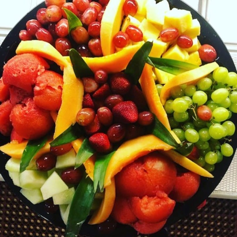 A colorful fruit platter with watermelon, grapes, pineapple, cantaloupe, honeydew, and strawberries.