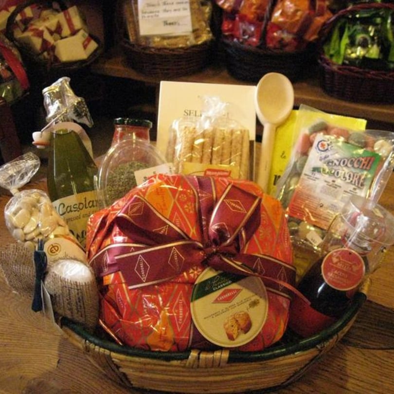A Tino's Delicatessen gift basket filled with Italian gourmet foods, including panettone, olive oil, and pasta.